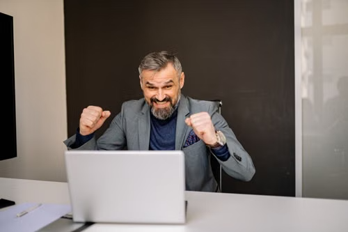 An agency professional celebrating a win at their laptop